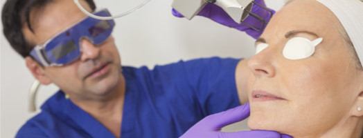 A cosmetic surgeon doctor giving laser skin treatment to the face of a senior female woman